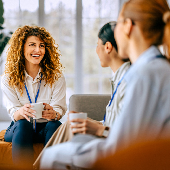 Hymyilevät naiset kahvitauolla.