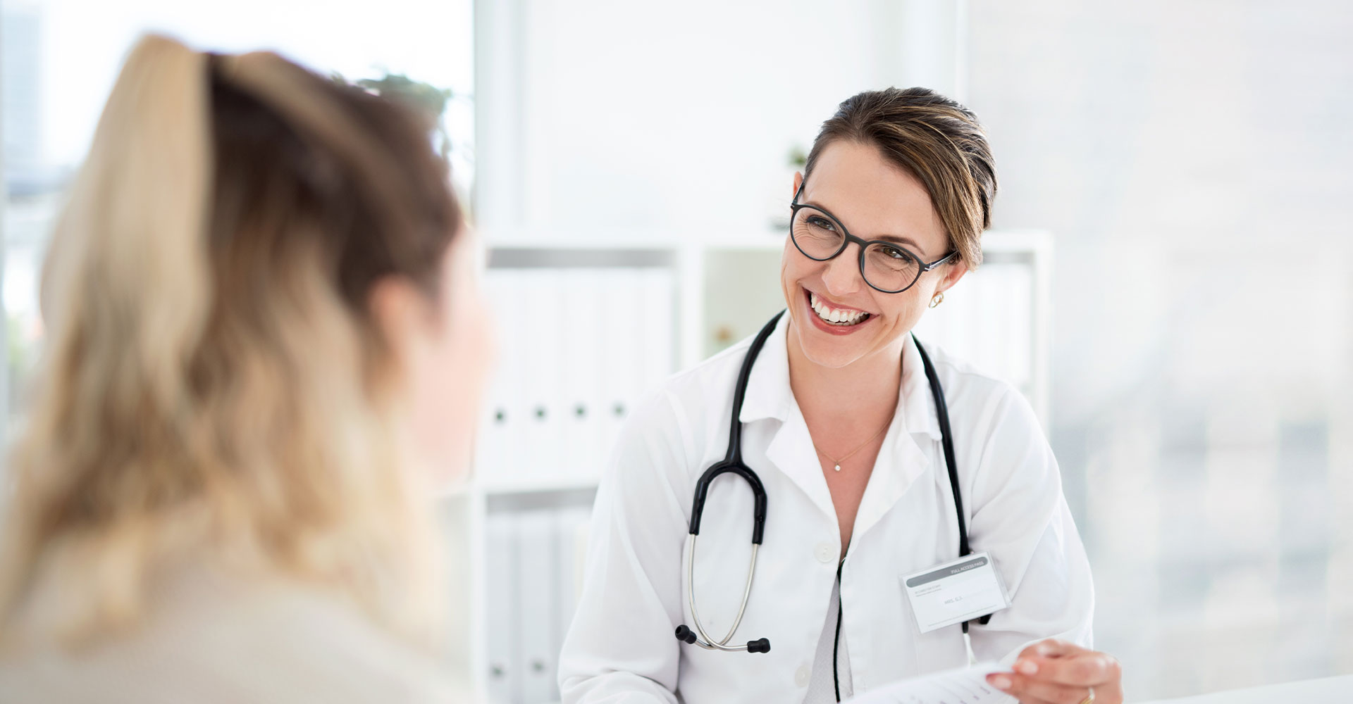 Hymyilevä hammaslääkäri keskustelemassa potilaan kanssa.