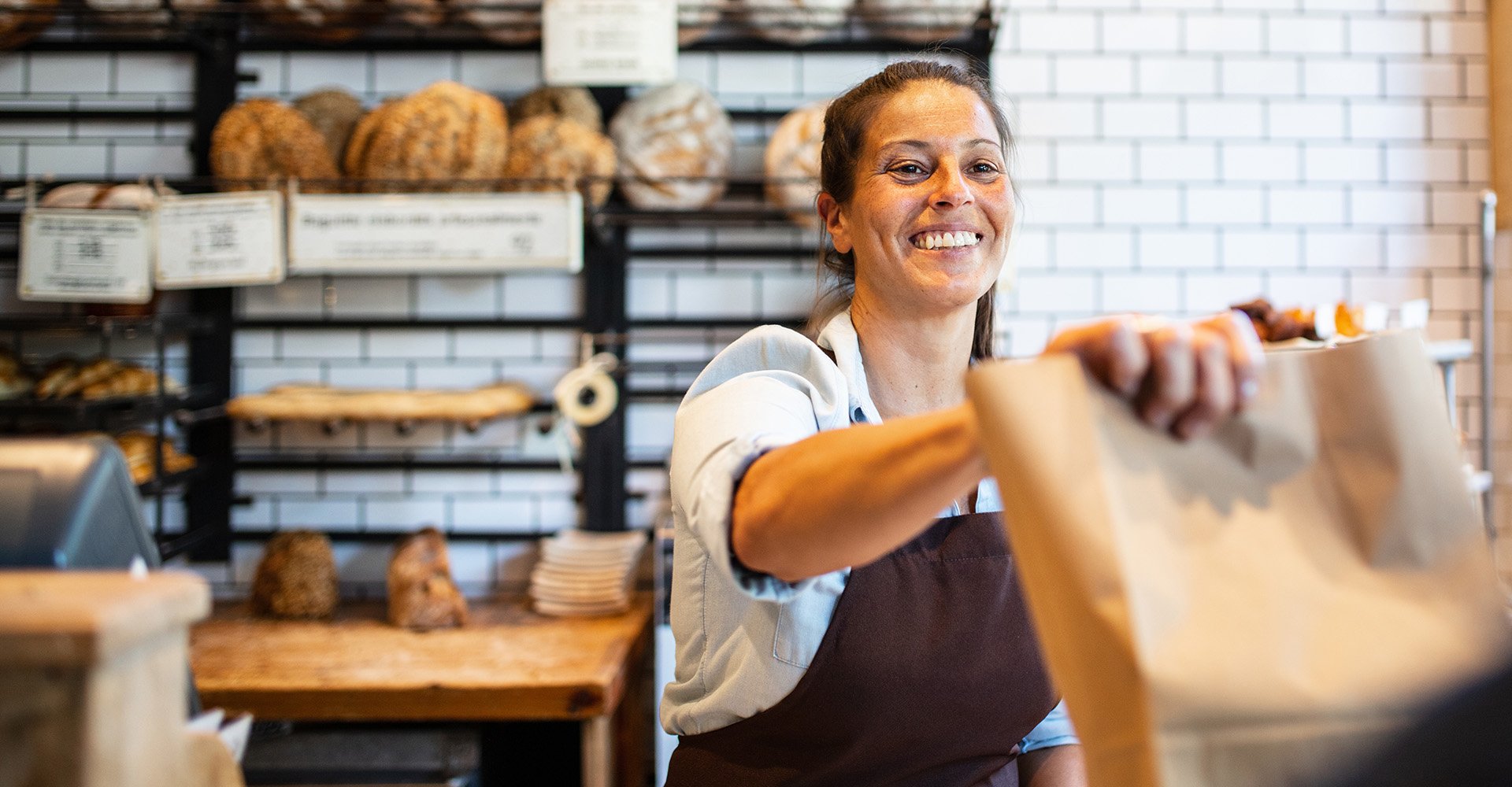 Leipomon hymyilevä työntekijä asiakaspalvelutilanteessa.