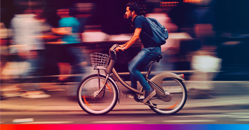 Mies pyöräilee kaupungin vilskeessä.