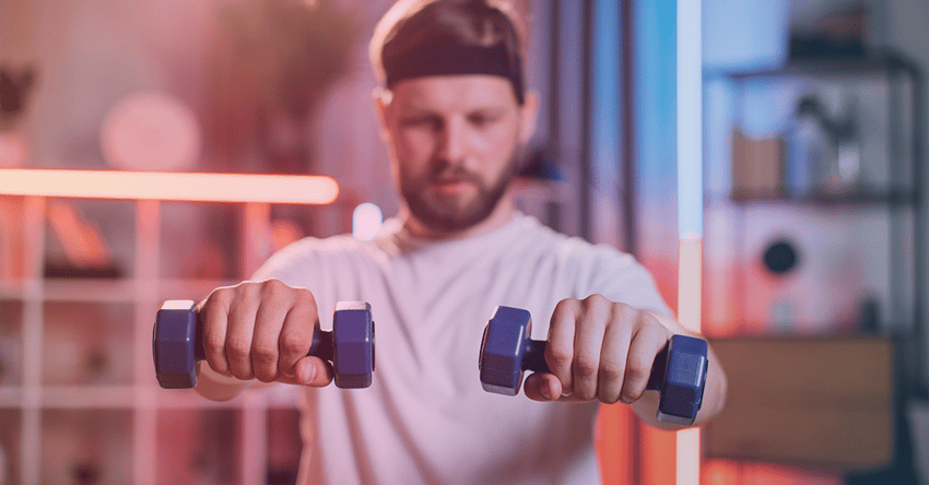Smiling man using dumbells in home workout 1200x627 gradient