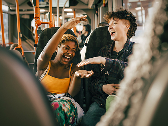 Nauravat ystävykset bussimatkalla.