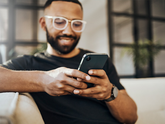 Hymyilevä henkilö selaamassa puhelinta.