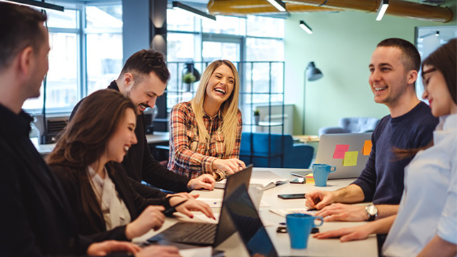 People at the office's group working space brainstorming together and smiling.